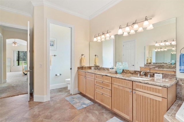 bathroom with toilet, tile patterned flooring, crown molding, vanity, and ceiling fan