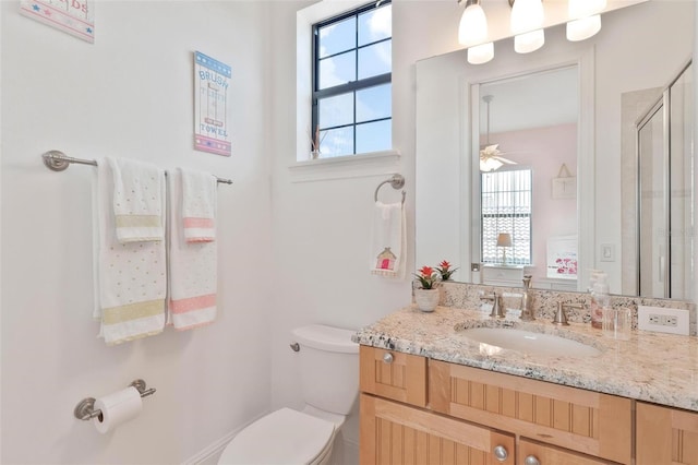 bathroom featuring vanity, toilet, walk in shower, and ceiling fan