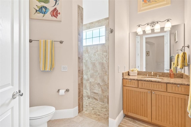 bathroom with vanity, tiled shower, toilet, and tile patterned flooring