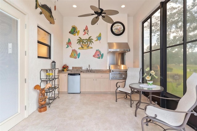 interior space with light tile patterned floors, wall chimney exhaust hood, sink, and stainless steel dishwasher