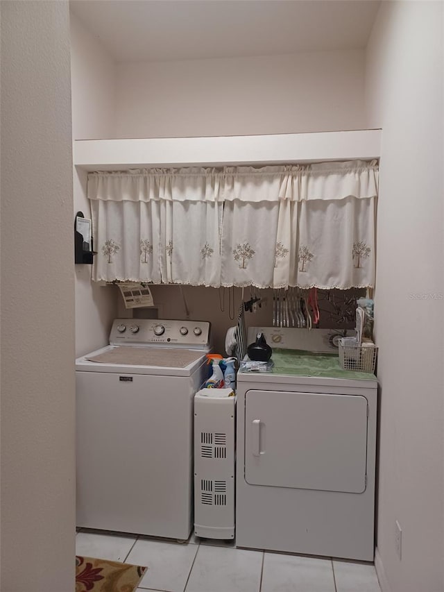 laundry area with washer and clothes dryer and light tile patterned floors