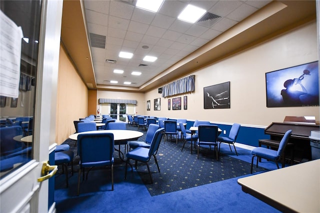 carpeted dining space with a paneled ceiling