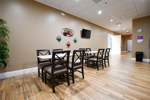 dining area with a paneled ceiling and light hardwood / wood-style floors