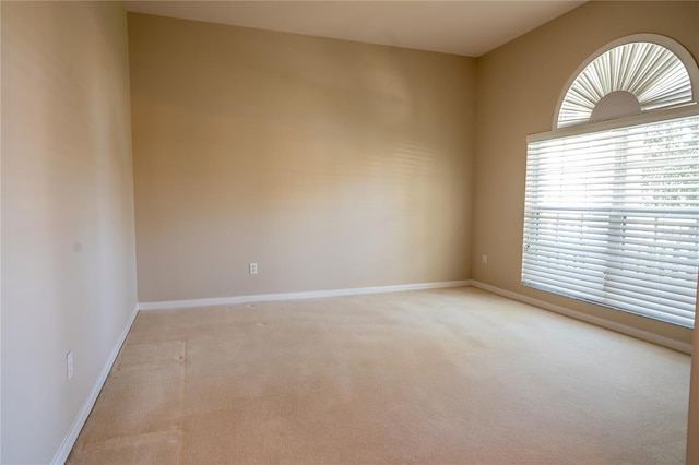 unfurnished room featuring baseboards and light colored carpet