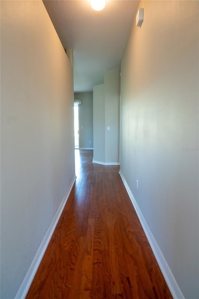 hall with baseboards and wood finished floors