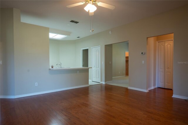 empty room with visible vents, baseboards, wood finished floors, a ceiling fan, and a sink