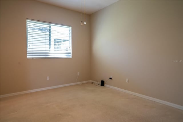 unfurnished room featuring baseboards and light carpet