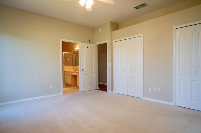 unfurnished bedroom with visible vents, two closets, ensuite bathroom, carpet flooring, and baseboards