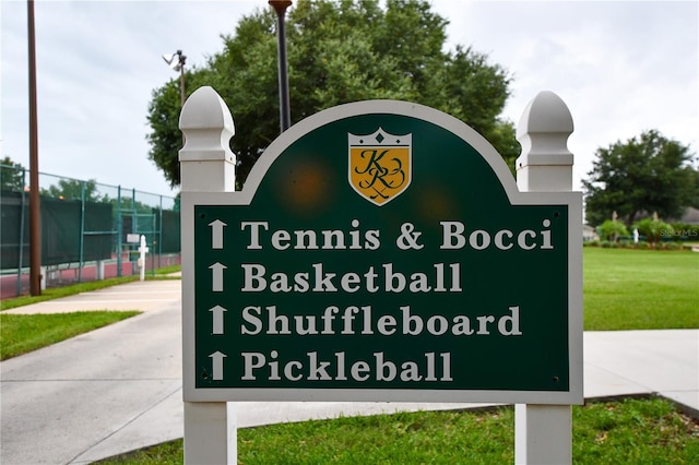 community sign with fence and a lawn