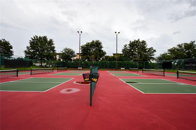 view of tennis court featuring community basketball court and fence