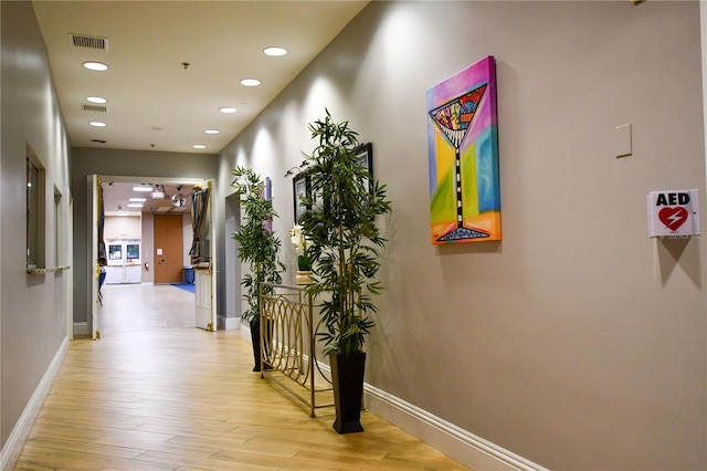 hallway featuring recessed lighting, visible vents, baseboards, and light wood finished floors