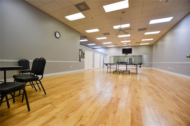 rec room featuring a drop ceiling, baseboards, and light wood-style floors