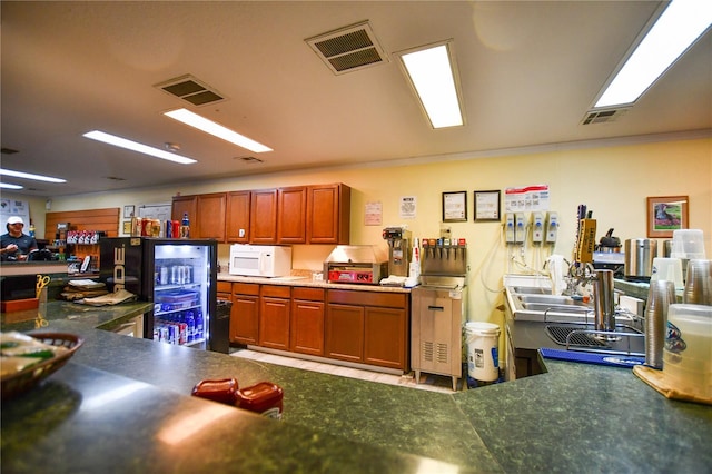 kitchen featuring brown cabinetry, white microwave, and visible vents