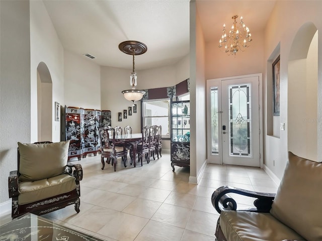 tiled entrance foyer featuring a notable chandelier and a towering ceiling