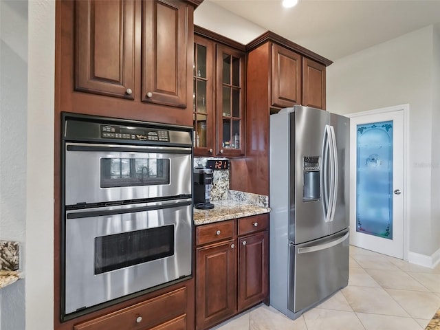 kitchen featuring light stone counters, stainless steel appliances, and light tile patterned floors