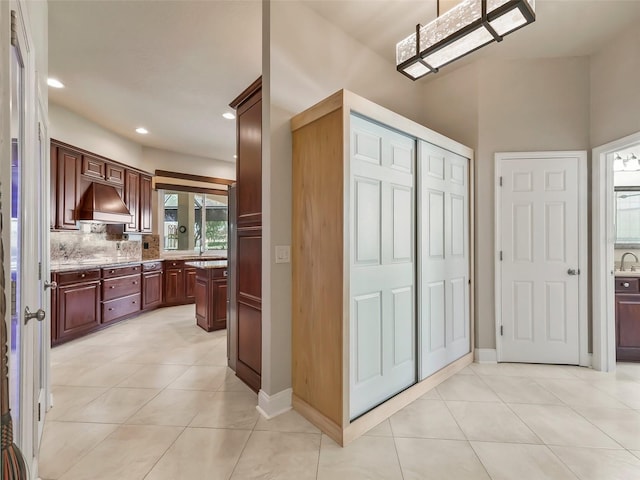 kitchen with light stone counters, custom range hood, tasteful backsplash, and light tile patterned floors