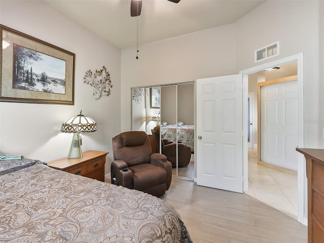 bedroom with a closet, ceiling fan, a towering ceiling, and light hardwood / wood-style floors