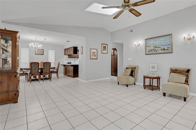 living room featuring ceiling fan with notable chandelier, lofted ceiling with skylight, and light tile patterned floors