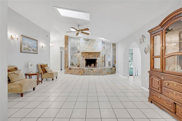 tiled living room featuring vaulted ceiling, ceiling fan, and a fireplace