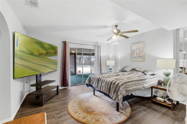 bedroom with ceiling fan, access to exterior, dark wood-type flooring, and a textured ceiling