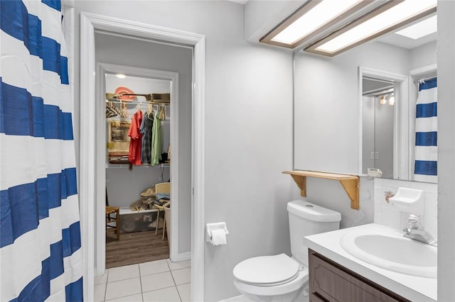 bathroom featuring tile patterned floors, walk in shower, vanity, and toilet