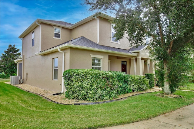 view of side of property with a lawn and central AC