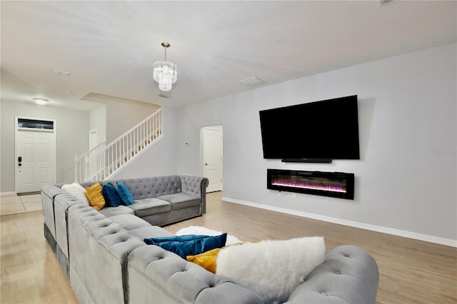 living room featuring an inviting chandelier, light wood-type flooring, and a textured ceiling