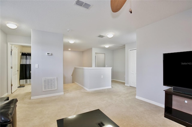 living room with ceiling fan, light colored carpet, and a textured ceiling