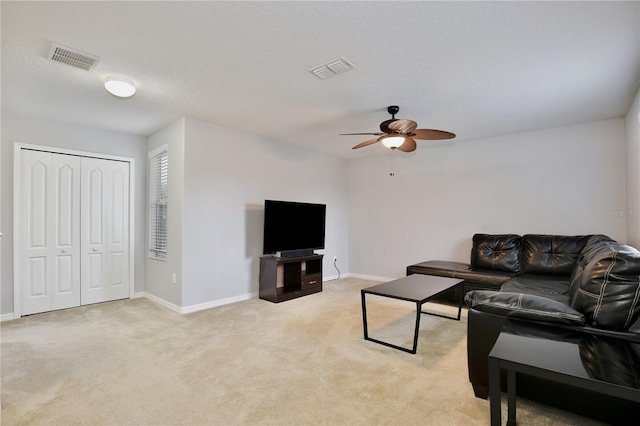 living room featuring ceiling fan, a textured ceiling, and light carpet