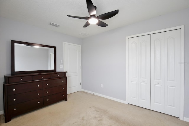 unfurnished bedroom featuring light carpet, a closet, ceiling fan, and a textured ceiling