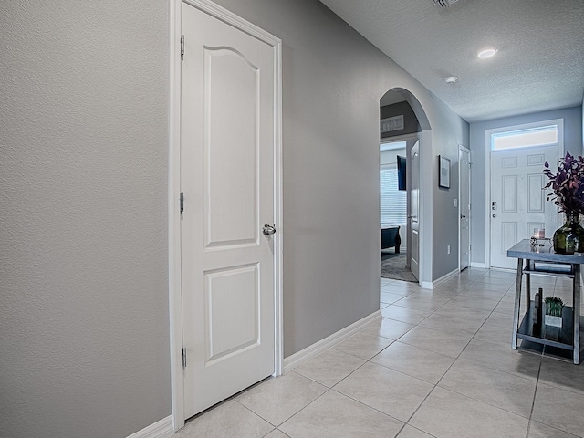 hall with light tile patterned floors and a textured ceiling