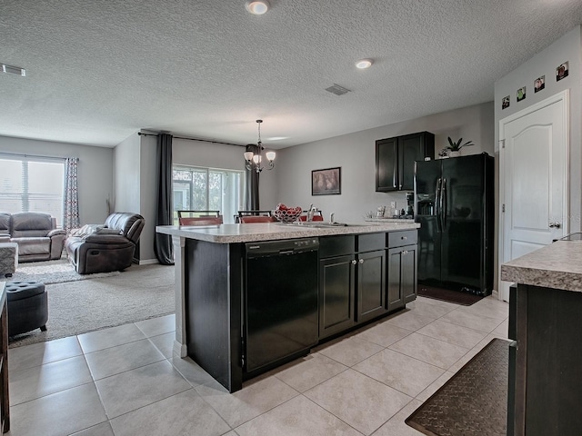 kitchen with a healthy amount of sunlight, a center island, black appliances, and decorative light fixtures