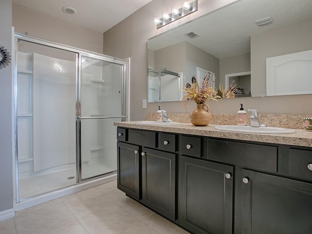 bathroom with tile patterned floors, vanity, a textured ceiling, and walk in shower