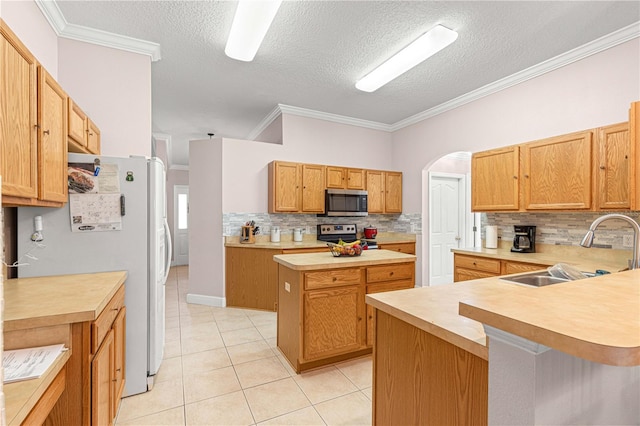 kitchen with sink, a kitchen island, appliances with stainless steel finishes, light tile patterned floors, and crown molding