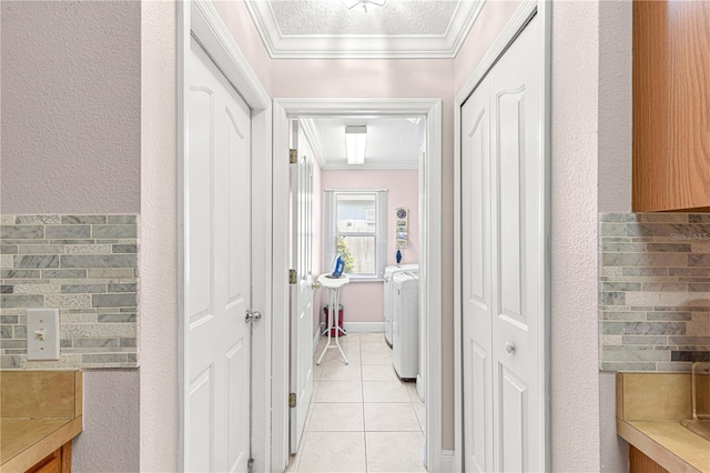 corridor featuring a textured ceiling, crown molding, light tile patterned floors, and washing machine and dryer