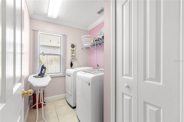 clothes washing area featuring a textured ceiling, crown molding, light tile patterned flooring, and washer and dryer