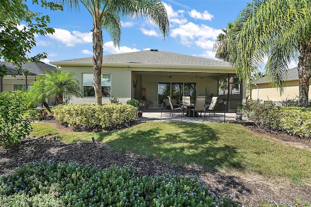 back of property with a yard, ceiling fan, and a patio area