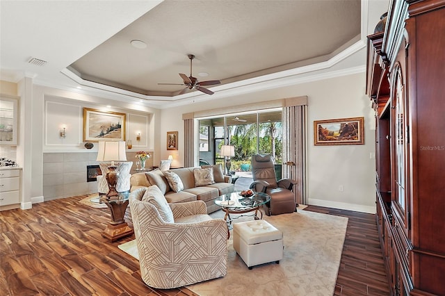 living room featuring a tray ceiling, hardwood / wood-style flooring, crown molding, and ceiling fan