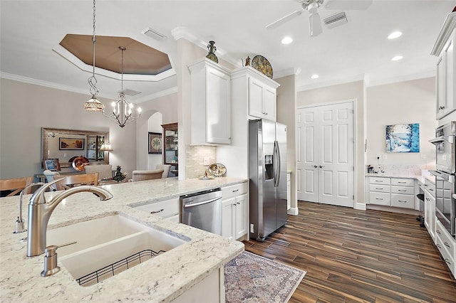 kitchen with stainless steel appliances, a raised ceiling, sink, pendant lighting, and white cabinets