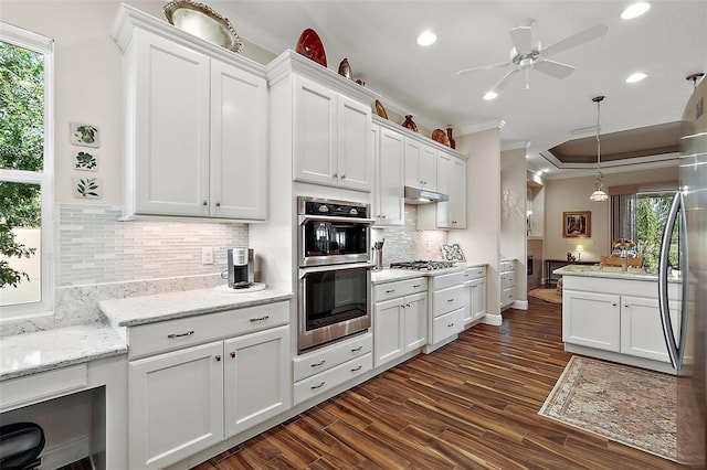 kitchen featuring white cabinetry, a healthy amount of sunlight, decorative light fixtures, and ornamental molding