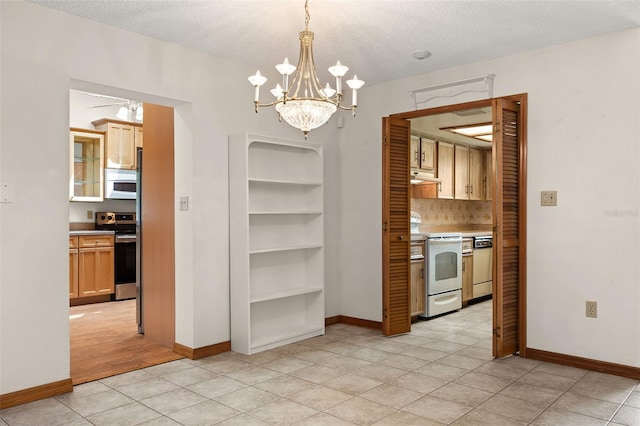 unfurnished dining area featuring ceiling fan with notable chandelier, a textured ceiling, and light tile patterned floors