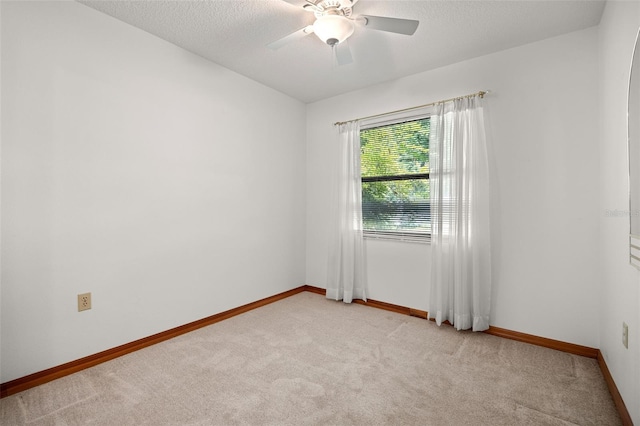 spare room with a textured ceiling, light colored carpet, and ceiling fan