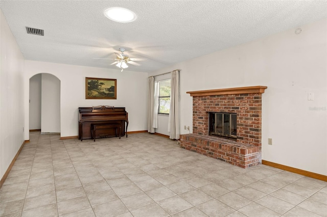 living room with ceiling fan, a textured ceiling, and a fireplace