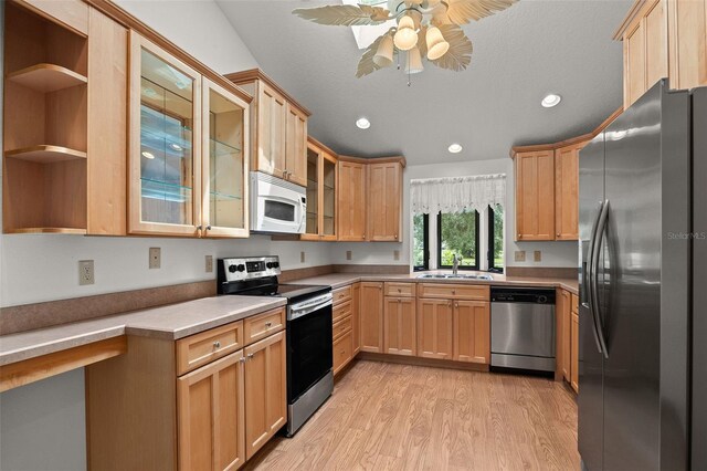 kitchen with appliances with stainless steel finishes, a textured ceiling, light wood-type flooring, ceiling fan, and sink