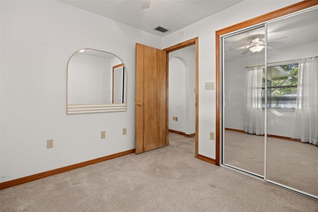 unfurnished bedroom with light carpet, a closet, ceiling fan, and a textured ceiling