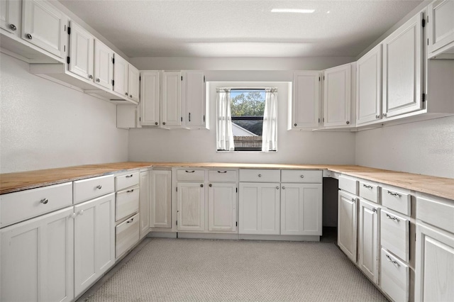 kitchen featuring a textured ceiling and white cabinetry