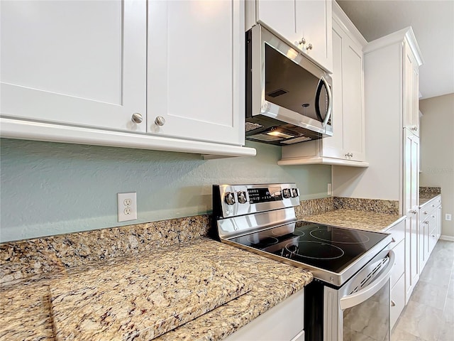 kitchen with white cabinets, stainless steel appliances, and light stone countertops