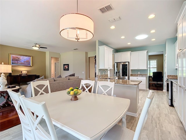 dining space with light hardwood / wood-style floors, sink, and ceiling fan