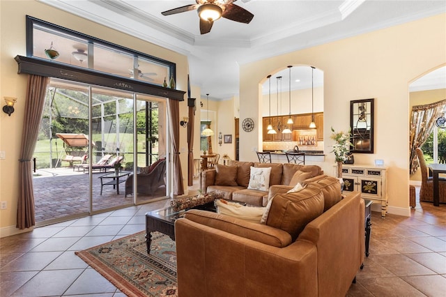 tiled living room featuring a raised ceiling, ornamental molding, ceiling fan, and a wealth of natural light