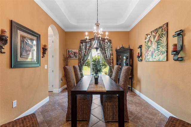 dining space with ornamental molding, a tray ceiling, and an inviting chandelier